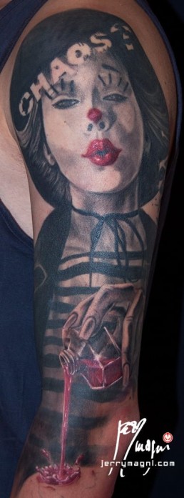 Quarta sedua Tatuaggio trash polka a tutta manica con donna pagliaccio su spalla, macchie, testa di manichino su cui cola del sangue tenuto dalla donna, delle monete norvegesi delle macchie e delle scritte. Realizzato in modo spettacolare da Jerry Magni, miglior tatuatore, Bergamo, Milano, Lugano, Brescia, Como, Lecco.