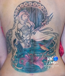 sesta seduta Copertura vecchio tatuaggio e sviluppo nuovo tatuaggio a tutta schiena con Anfitrite, dea della mitologia greca, che emerge dalle acque. Indossa un’armatura sexy, ha capelli fluenti che circondano l’immagine in cui vediamo anche tue colibrì che volano su un giglio rosa. Dietro alla dea una decorazione ispirata alle opere di Mucha. Realizzato da Jerry Magni, miglior tatuatore, Bergamo, Milano, Brescia, Piacenza, Lecco, Como, Italia, Lombardia, provincia, Lugano.