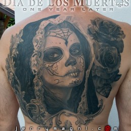 Black and grey Back piece tattoo. Portrait of a beautiful girl with the typical make up from the Mexican day of the dead, on her head a black lace veil, behind her a couple of roses, everything surrounded by filigree. Outstanding piece of art, masterfully done by by the best tattoo artist Jerry Magni, Bergamo, Milan, Lugano, Italy.