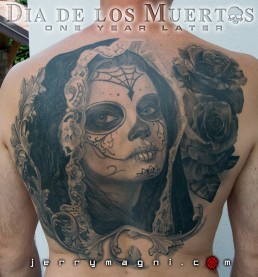 Black and grey Back piece tattoo. Portrait of a beautiful girl with the typical make up from the Mexican day of the dead, on her head a black lace veil, behind her a couple of roses, everything surrounded by filigree. Outstanding piece of art, masterfully done by by the best tattoo artist Jerry Magni, Bergamo, Milan, Lugano, Italy.