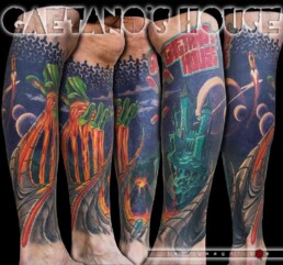 Tatuaggio surreale su polpaccio con un castello stile cartoon, una mano verde che versa lava, sullo sfondo un vulcano che erutta e un cielo viola con diverse lune. Al di sotto delle punte biomeccaniche. Il tatuaggio si chiude con un tema grafico e la scritta che da titolo all'opera. Eseguito da Jerry Magni, Bergamo, Milano, Lecco