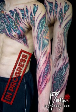 Tatuaggio biomeccanico con strappi nella pelle da cui vediamo dei tubi fuoriuscire dalla carne, sviluppato su torace e braccio, realizzato a mano libera da Jerry Magni, miglior tatuatore, Bergamo, Milano, Lugano, Brescia, Como, Lecco