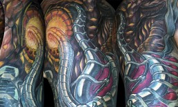 dettagliospalla di Tatuaggio biomeccanico a colori a tutta manica. Inserti metallici nella carne, tubi e artigli. Opera di Jerry Magni, miglior tatuatore, Bergamo, Milano, Lugano, provincia.